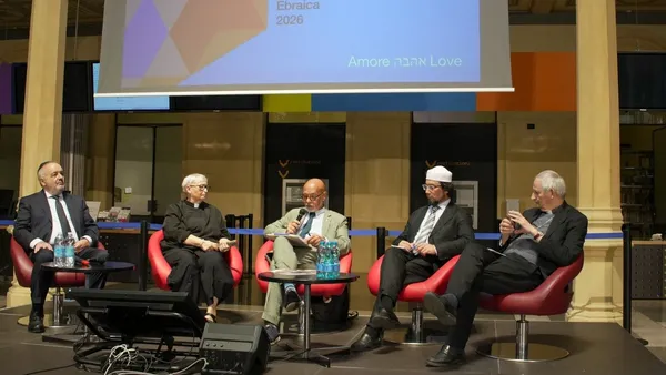 The panel "Children ask, religions answer" on stage at Biblioteca Salaborsa in Bologna, under a screen reading Love.