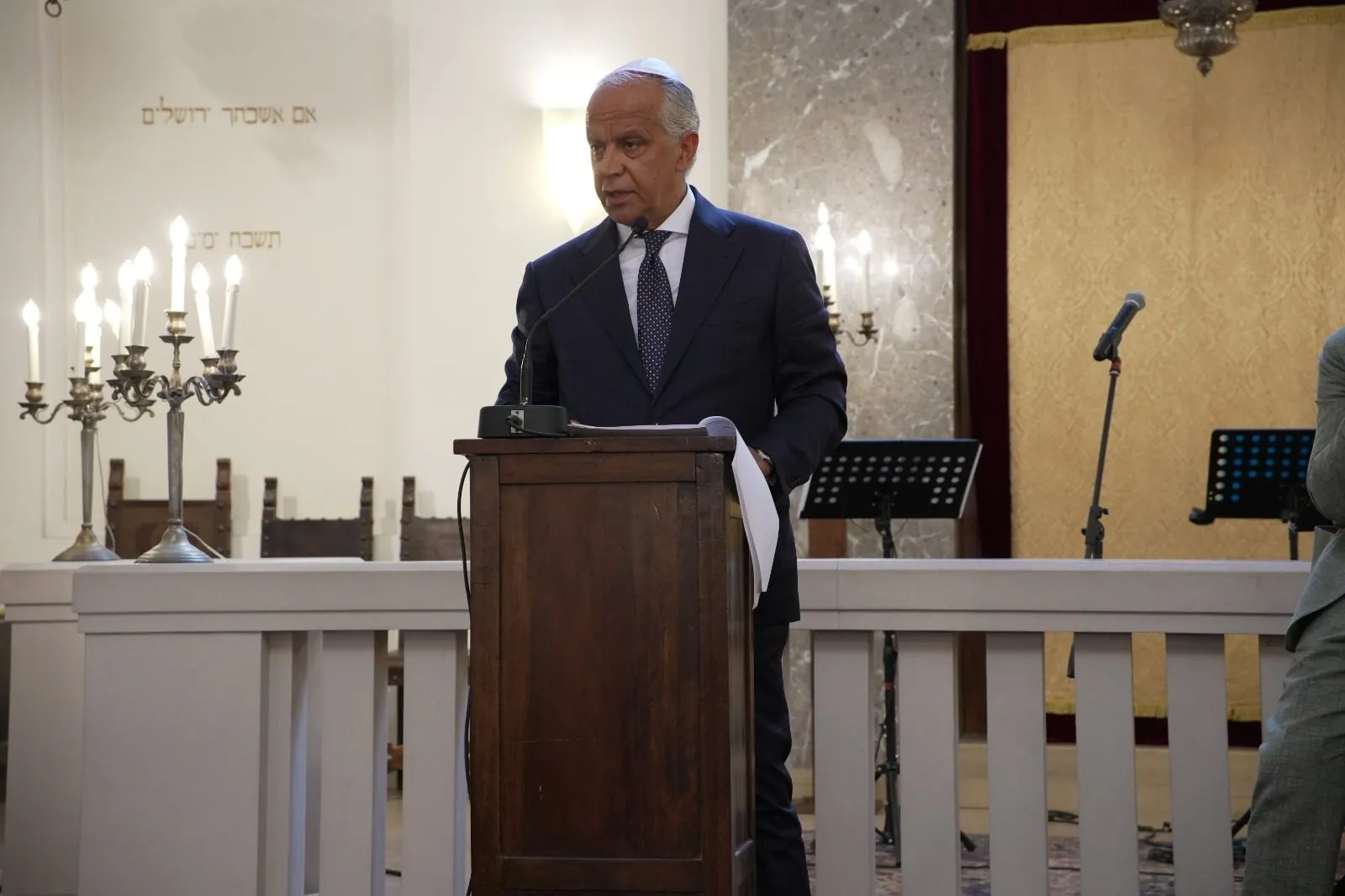 Italian Minister of the Interior Matteo Piantedosi speaking at a lectern in the Synagogue of Bologna.