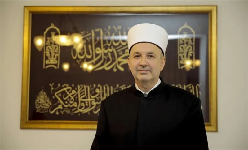 Portrait of Reisul-ulema Prof. Dr Nedžad Grabus standing in front of framed Islamic calligraphy.
