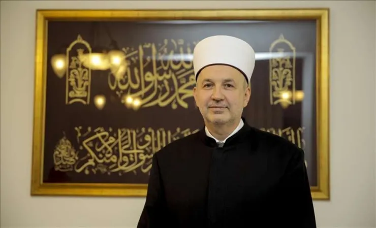 Portrait of Reisul-ulema Prof. Dr Nedžad Grabus standing in front of framed Islamic calligraphy.